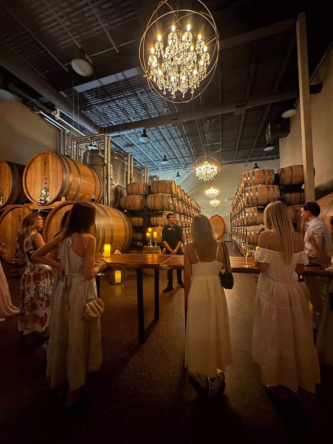 Members in white dresses in a candlelit barrel cellar