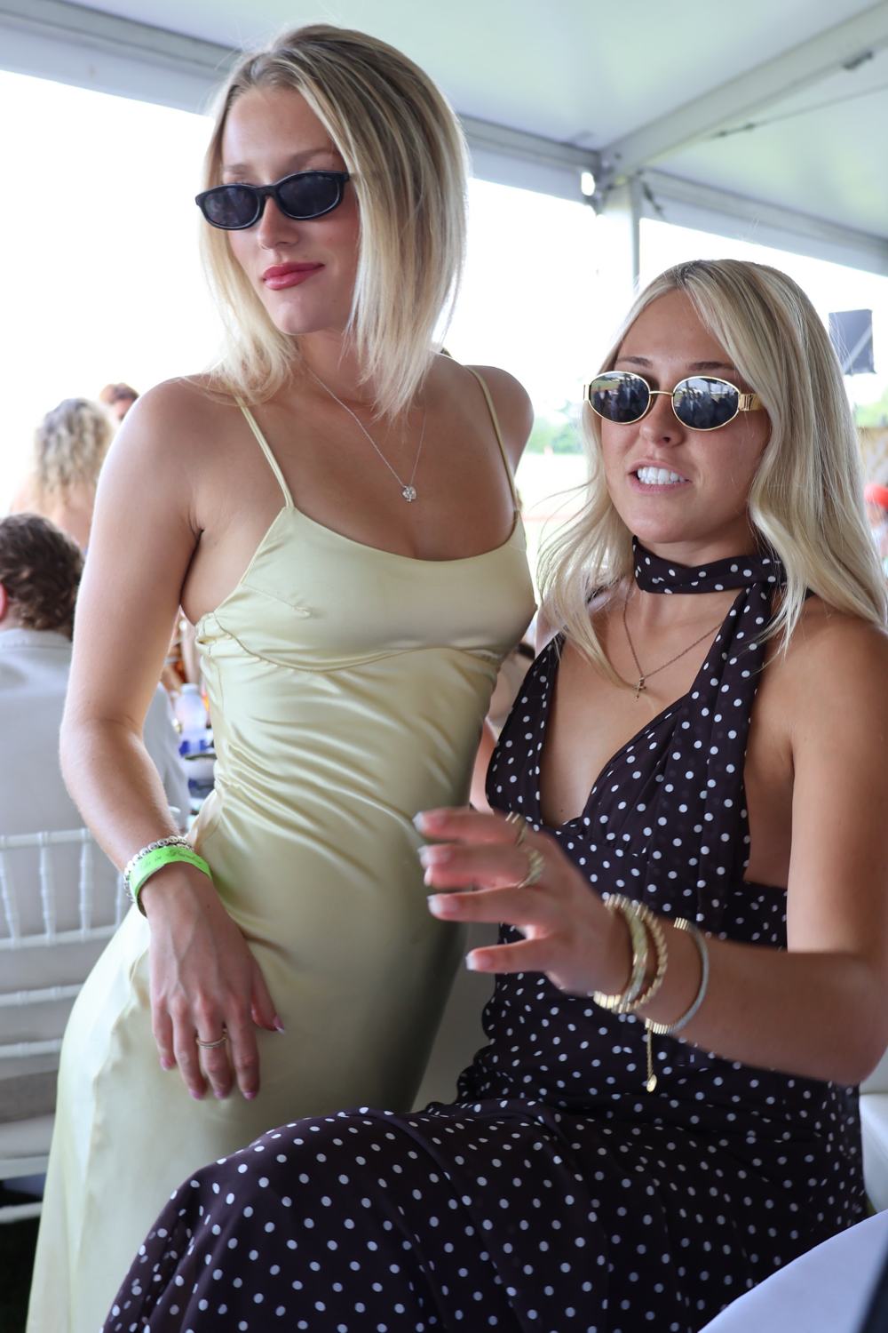 Two members with a glass under the marquee at the polo