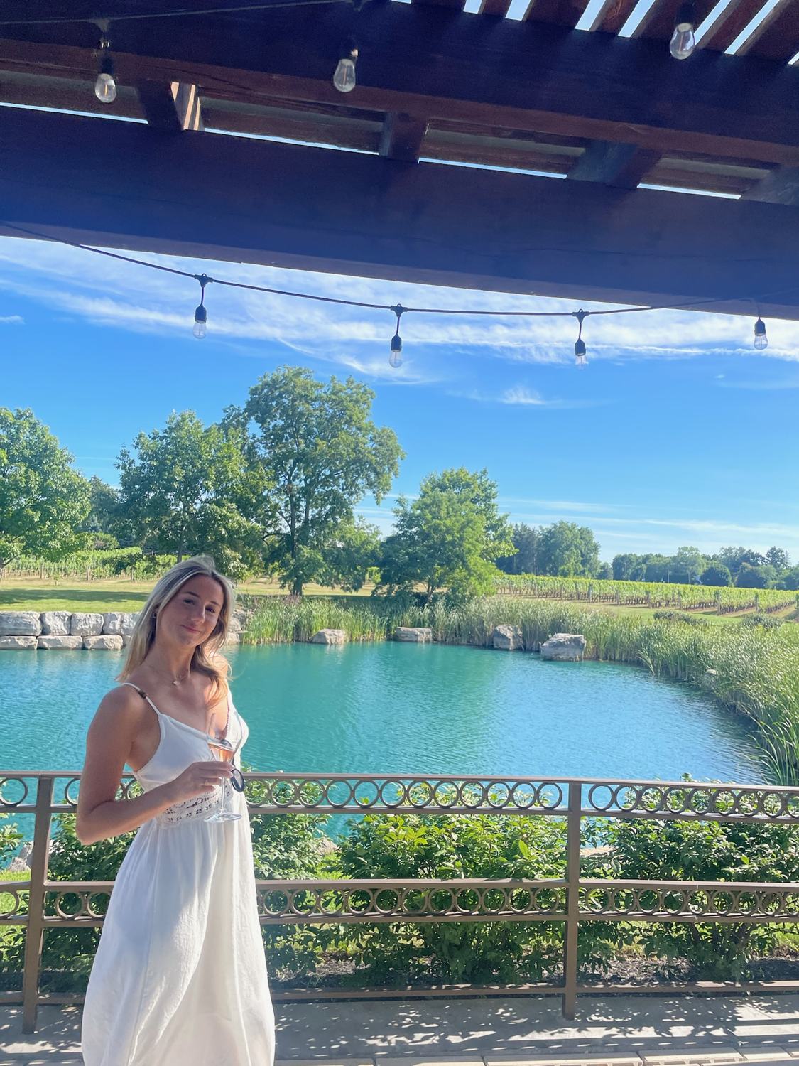 A member holding a glass of wine beside the pond