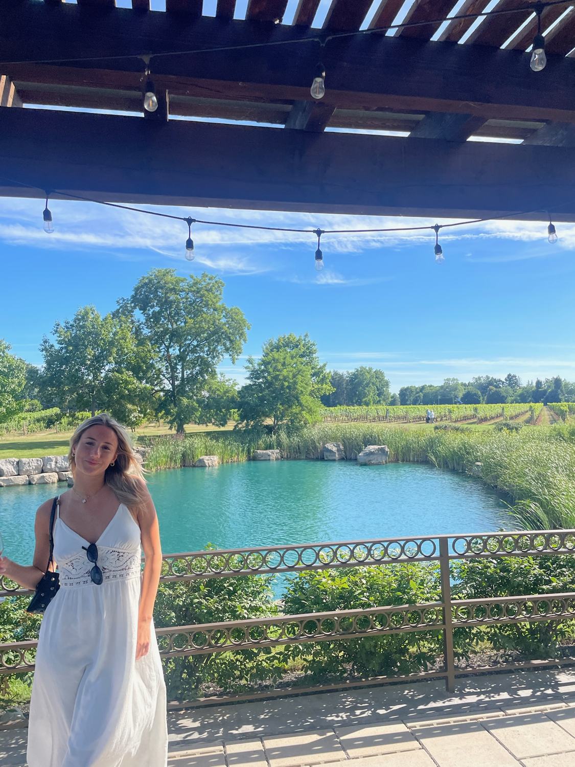 A member in a white dress beside a turquoise pond