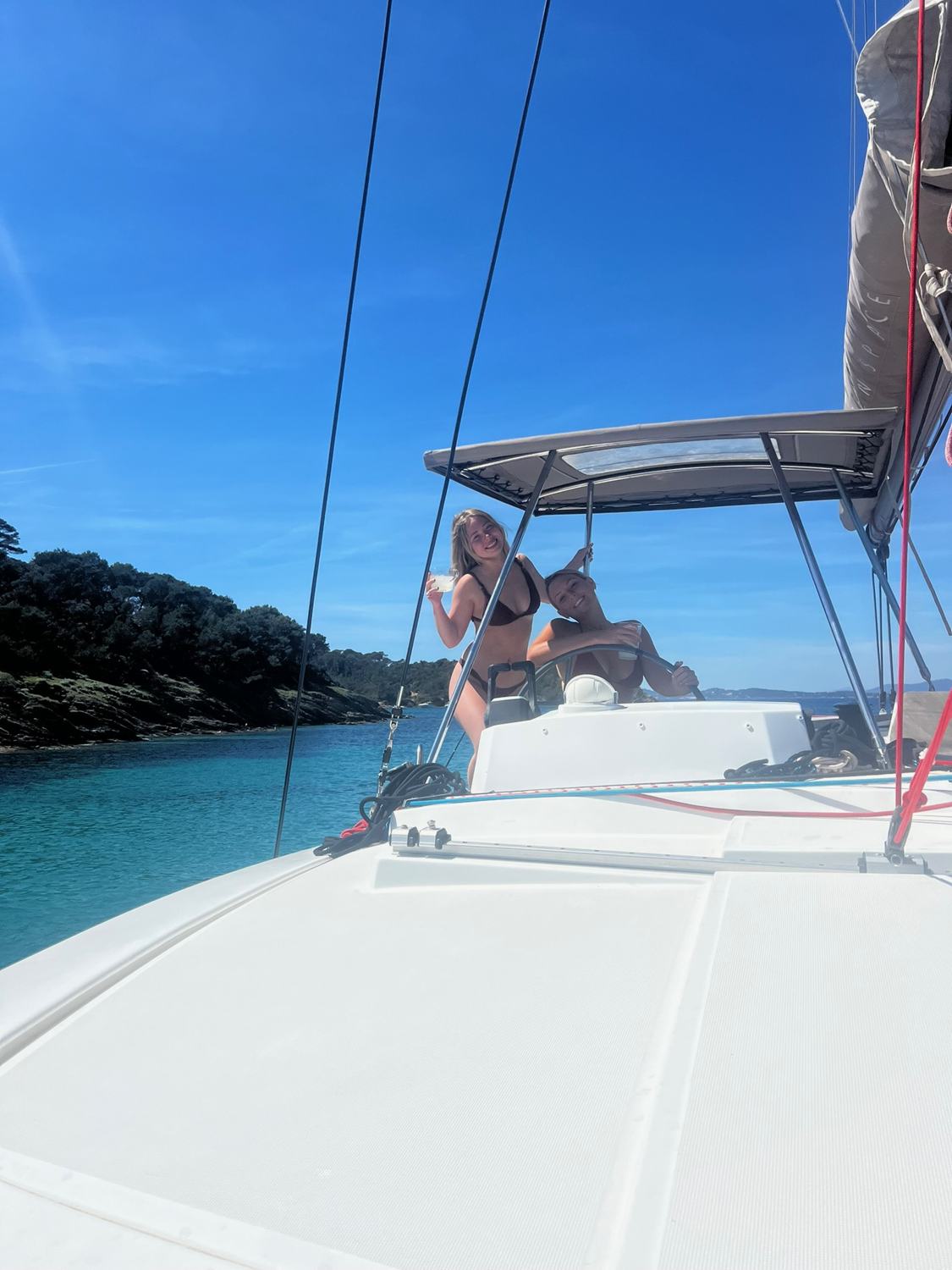 A catamaran at anchor in a turquoise cove