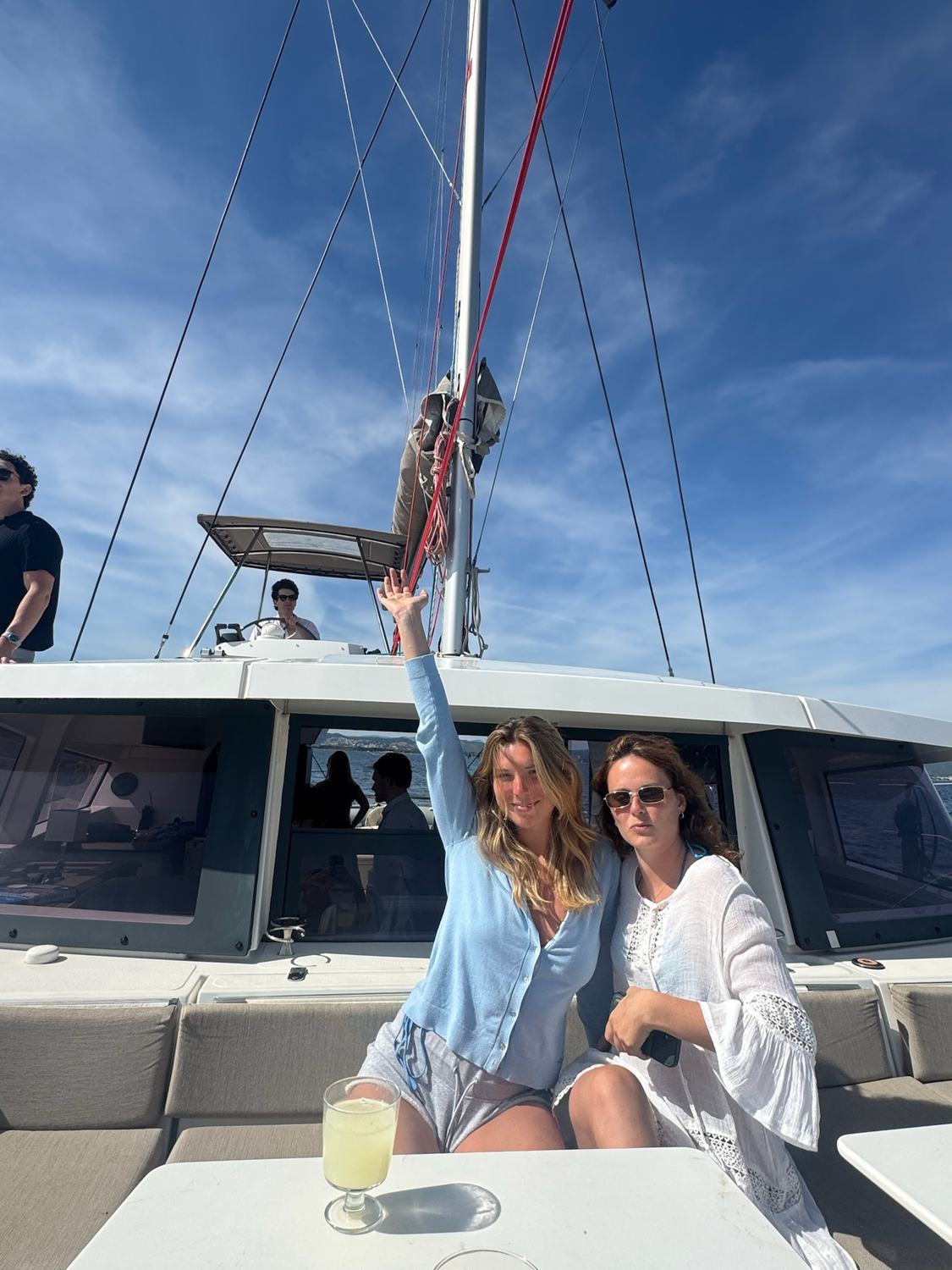 Two members raising a glass on the deck of the catamaran